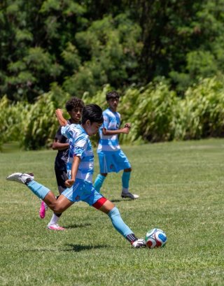 An FC Hawaiʻi player strikes the ball on a grass field, from the @fc_hawaii Instagram post.